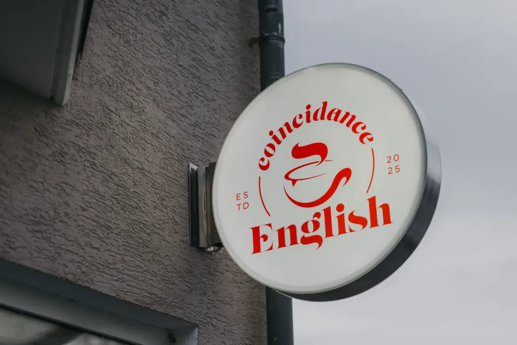 Rundes Werbeschild von coincidance English in Worbis mit Logo an Gebäudefassade montiert