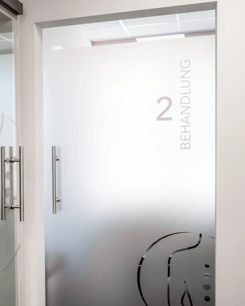 Milchglastür mit Beschriftung „2 Behandlung“ in der Physiotherapie Sophie Klaus, dezentes Praxis-Leitsystem.