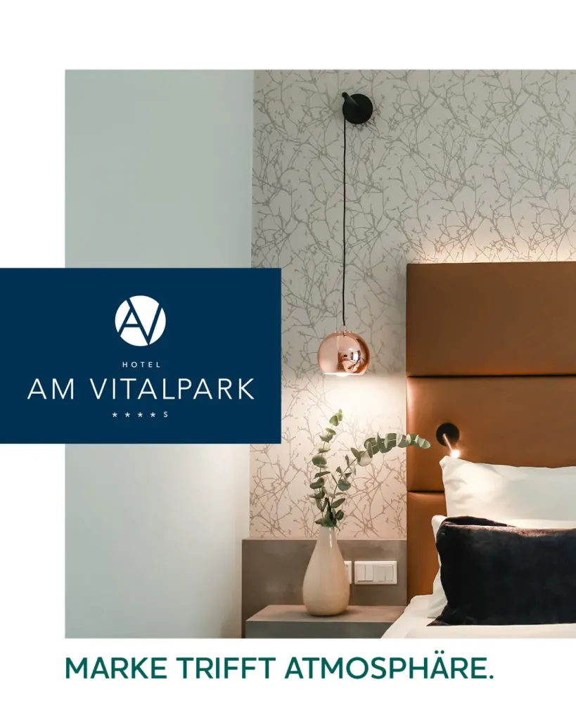 Hotelzimmer-Detail im Hotel am Vitalpark mit Logo, Wandlampe und stilvollem Nachttisch-Ambiente